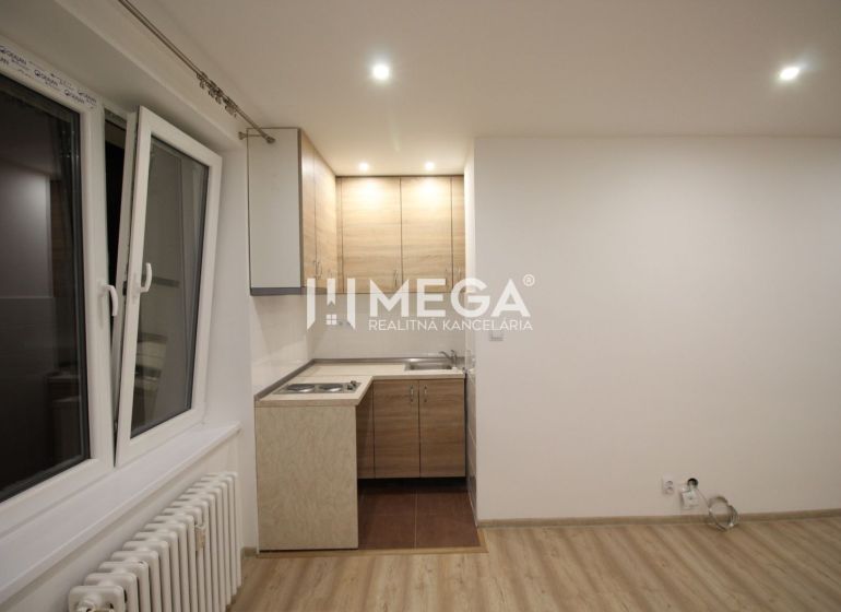 Na predaj garsónka na Sokolovskej ulici v meste Humenné - Kuchyňa v rekreačnom apartmáne s kuchynskou linkou a podlahou s dreveným dekorom.