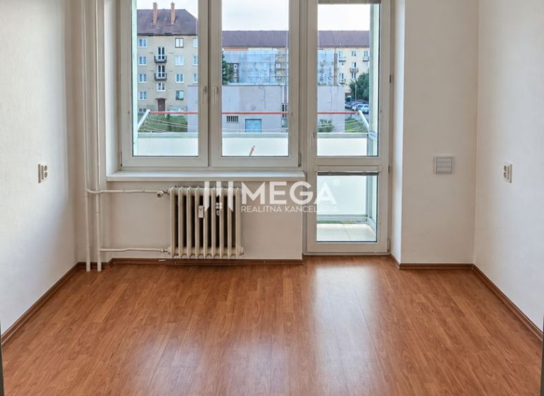 NA PREDAJ 2-izbový zrekonštuovaný byt s balkónom  v Humennom - Izba v 2-izbovom byte s podlahou s dreveným dekorom a veľkým oknom.
