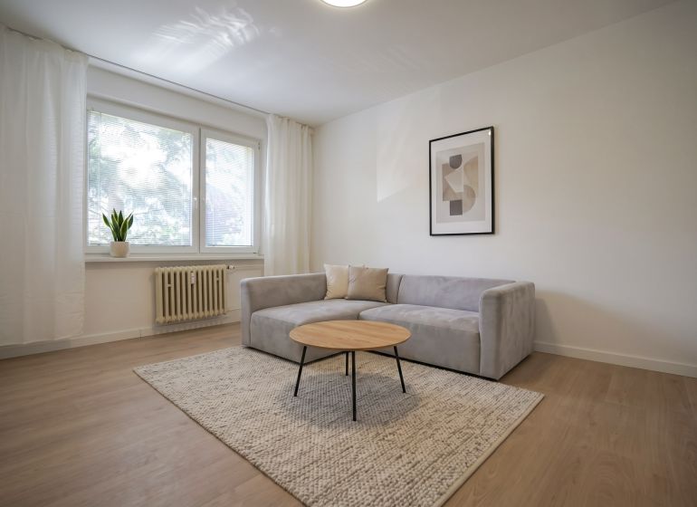 REZERVOVANÉ 1 izbový byt s balkónom - až 41m² N. DUBNICA - Obývačka v 1-izbovom byte s pohovkou, koberec a podlaha s dreveným dekorom.