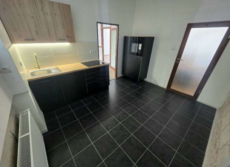 PRENÁJOM Bánovce nad Bebravou/2 IZBOVÝ BYT/CENTRUM-STRED/70m2 - Kuchyňa v 2-izbovom byte s čiernymi skrinkami a podlahou s textúrou.