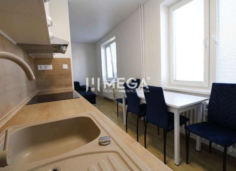 NA PRENÁJOM -  Zariadený 2 izbový byt s balkónom, Dobrianského, Humenn - Kuchyňa v 2-izbovom byte s bielym nábytkom, modrými stoličkami a podlahou s dreveným dekorom.
