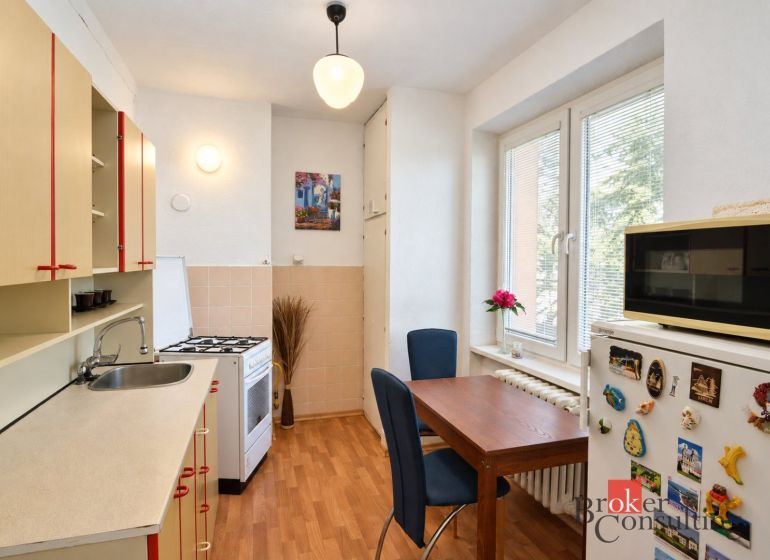 Svetlý a teplý 2-izbový byt s balkónom v centre Spišskej Novej Vsi (52 - Kuchyňa v 2-izbovom byte s podlahou s dreveným dekorom, jedálenským stolom a modernou výbavou.