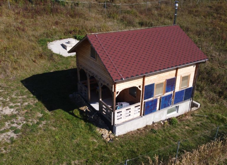 Na predaj Chata Horná Breznica, pozemok 5084 m2, POLOSAMOTA - Chata v Horná Breznici s dreveným obkladom a červenou strechou na zelenom pozemku.