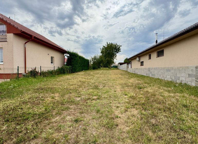 NA PREDAJ stavebný pozemok Močenok - Pozemok na bývanie v Močenku medzi rodinnými domami s trávnatým porastom.