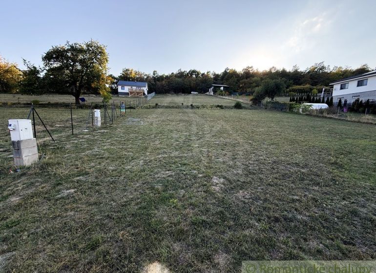 3106m2 stavebný pozemok nad priehradou v Krupine - Záhrady v Krupine, domy na svahu, tráva a stromy, vidno rozvodnú skriňu.