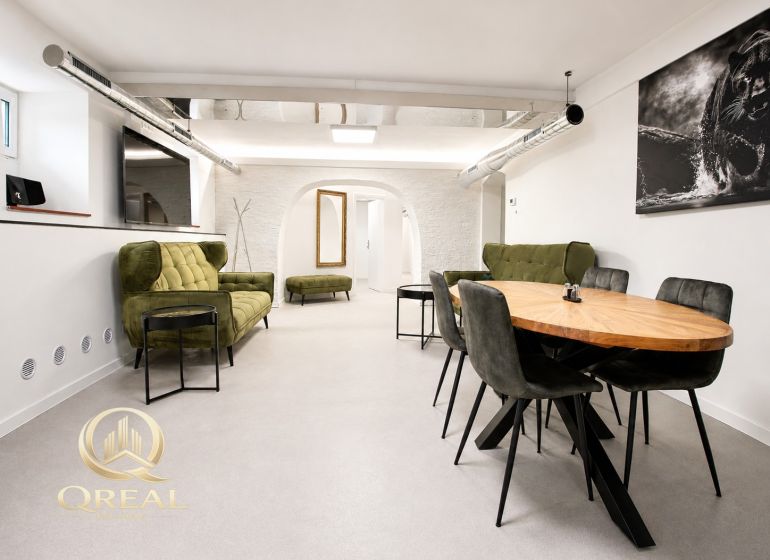 **Hotový priestor. Povolené ubytovanie. Pripravené zarábať**Airbnb** - Priestranná obývacia izba s dreveným jedálenským stolom a zelenými sedačkami.