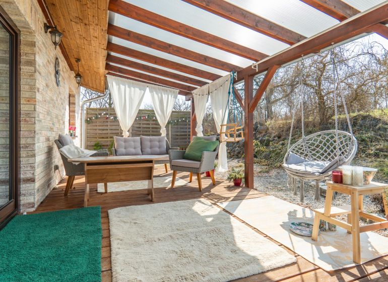 Rodinný dom a pozemok 8 500 m² - Zastrešená terasa s ratanovým nábytkom na pozemku pre bývanie v Dolnom Lopašove.