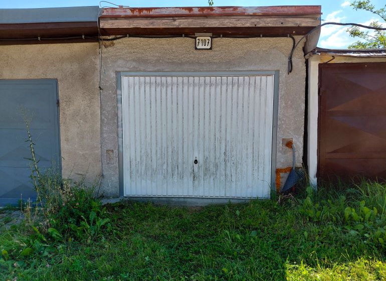 Na predaj garáž s elektrinou – Martin, Podháj - Garáže v Martine s kovovými dverami, obklopené zelenou trávou.