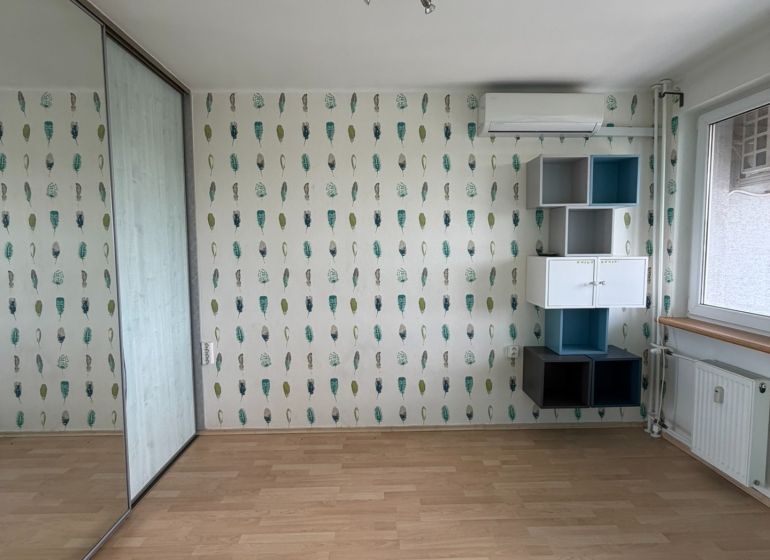 PRENÁJOM- 2-izbového bytu v centre mesta Šaľa – pešia zóna  - Izba v 2-izbovom byte s podlahou s dreveným dekorom a zrkadlovou skriňou.