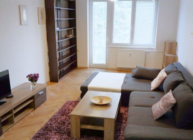 Svetlý, kompletne zariadený 2i byt s balkónom blízko centra Trenčína - Obývačka v 2-izbovom byte s podlahou s dreveným dekorom a pohodlnou pohovkou.
