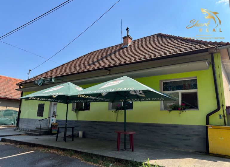 Obchodný priestor s ubytovacím zariadením - Exteriér gastronomických priestorov v Kozárovciach so slnečníkmi nad vchodom.