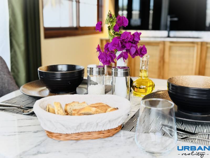 APARTMÁN NA PREDAJ V PAJE, ZANZIBAR - Stôl je prestretý na raňajky: kvetiny, chlieb, a 1-izbový byt.