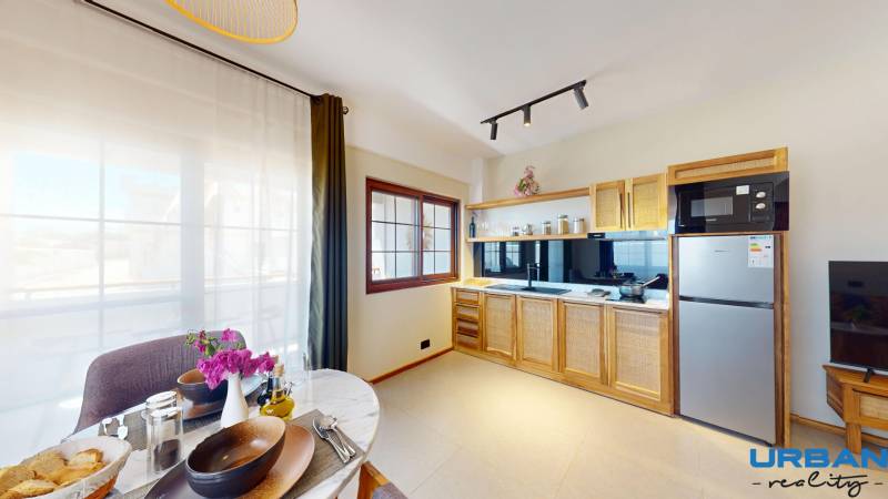 APARTMÁN NA PREDAJ V PAJE, ZANZIBAR - Kuchyňa s drevenou skrinkou, jedálenským stolom a 1-izbový byt so svetlým interiérom.