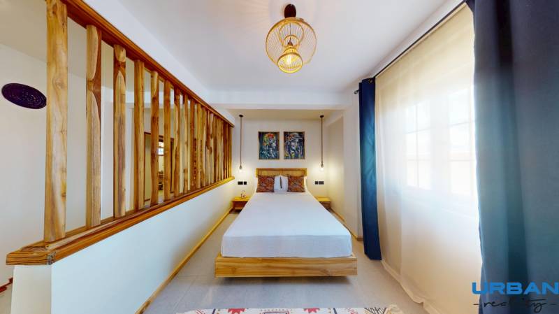 APARTMÁN NA PREDAJ V PAJE, ZANZIBAR - Na obrázku je útulná spálňa s dreveným rámom, osvetlená lustrami a 1-izbový byt.