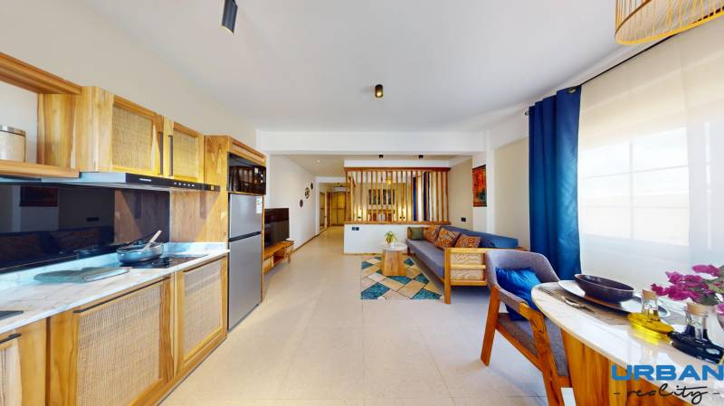 APARTMÁN NA PREDAJ V PAJE, ZANZIBAR - Interiér a 1-izbový byt s drevenými prvkami, farebným nábytkom a praktickou kuchynskou linkou.