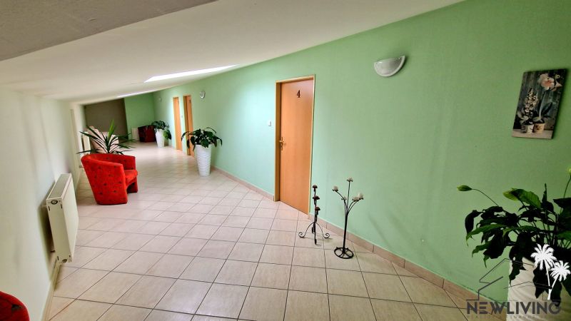 POLYFUNKČNÝ OBJEKT v Topoľčanoch NA PREDAJ - Chodba v budove s červenými kreslami, zelenými stenami, rastlinami. U Škultétyho.