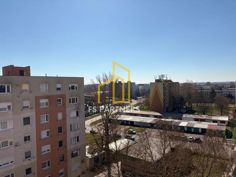 Kompletne zariadený 2-izbový byt (pôvodne 3-izb.) – Vodná ul. Komárno - Pohľad z 3-izbového bytu, na ulici Vodná, na sídlisko s parkoviskom a stromami.