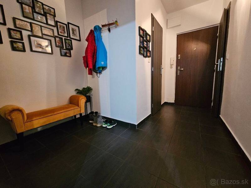 Predaj 3 izbový moderný byt v centre s balkónom - Chodba v 3-izbovom byte na ulici Okružná. Je zariadená vešiakom a lavicou.