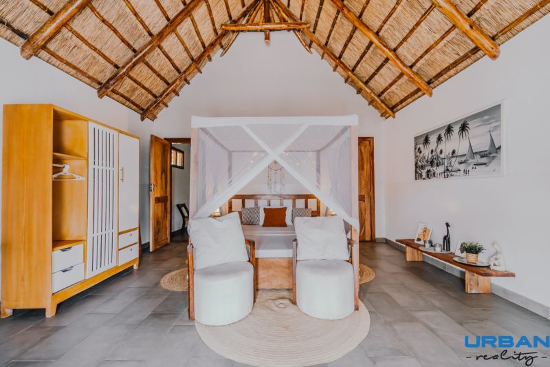 ZARIA GARDEN BUNGALOWS - Interiér izby so slamennou strechou, posteľou s baldachýnom a jednoduchou výstavbou domov.
