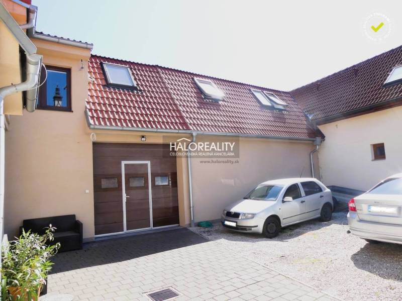 Predaj, rodinný dom Trnava, polyfunkčný objekt s veľ... - Rodinný dom v Trnave s hnedou garážou, sedlovou strechou a dvorom s lavičkou.