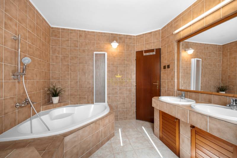 Priestranný 7-izbový dom na skok od centra – Senec - Kúpeľňa v rodinnom dome s hnedými obkladmi, vaňou a dvojitým umývadlom.