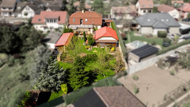 Priestranný 7-izbový dom na skok od centra – Senec - Rodinný dom v Senci obklopený záhradou a stromami, s červenou strechou.