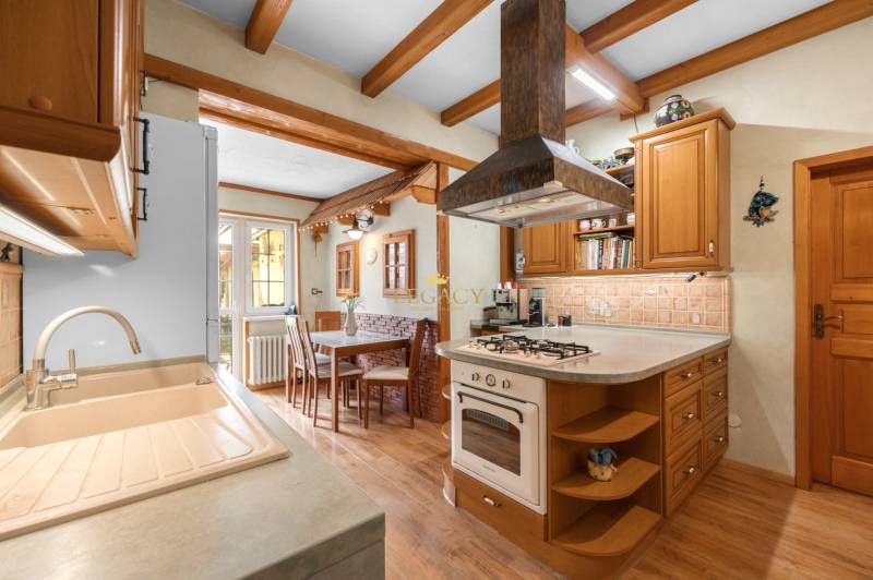 Priestranný 7-izbový dom na skok od centra – Senec - Kuchyňa v rodinnom dome s drevenými prvkami, varnou doskou a jedálenským stolom.