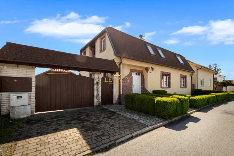 Priestranný 7-izbový dom na skok od centra – Senec - Rodinný dom v Senci so šikmou strechou a bránou v tichej ulici.