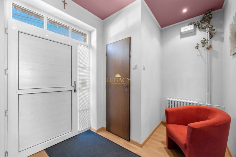 Priestranný 7-izbový dom na skok od centra – Senec - Interiér rodinného domu s výrazným červeným kreslom a vstupnými dverami.