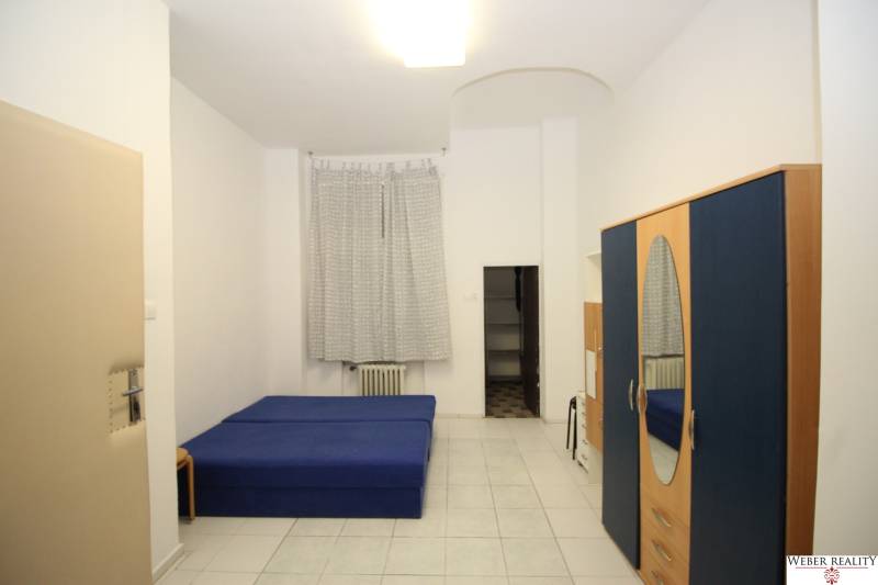Dáme do prenájmu 1-izb.byt priamo v centre na Gorkého ul.cena vrátaneE - Svetlý 1-izbový byt s modrou posteľou, šatníkovou skriňou a bielou dlažbou.