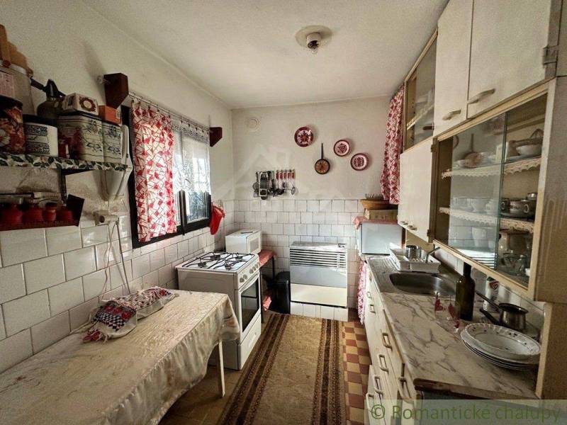 Rodinný domček na kopci vo vinárskej obci Veľký Kýr - Tradičná kuchyňa v rodinnom dome s rustikálnym vybavením, červenobiele závesy a dekorácie.