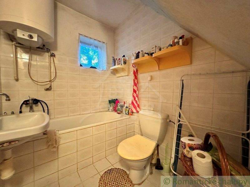 Rodinný domček na kopci vo vinárskej obci Veľký Kýr - Kúpeľňa v rodinnom dome: vaňa, umývadlo, WC, regály na toaletné potreby, košík.