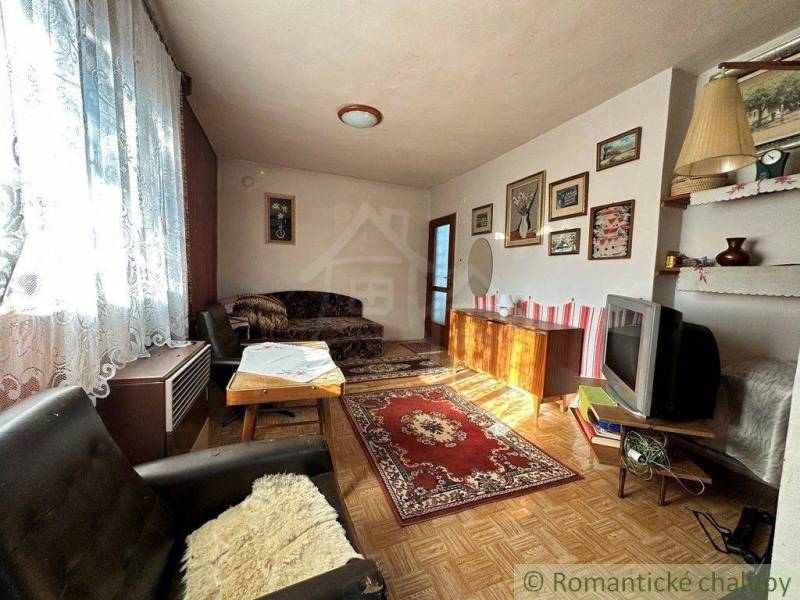 Rodinný domček na kopci vo vinárskej obci Veľký Kýr - Obývačka v rodinnom dome, s koberecmi, pohovkou, obrazmi a starou televíziou.