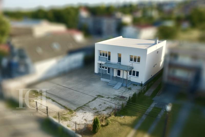 PRENAJOM | Kancelárie, administratíva, polyfunkcia, sklad, výroba - Biela budova kancelárií na Novozámockej ulici v Nitre s betónovým parkoviskom.