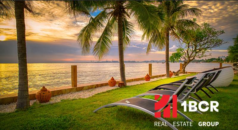PARADISE OCEAN VIEW PATTAYA - Lehátka pri mori obklopené palmami počas západu slnka vo výstavbe bytov v Pattayi.