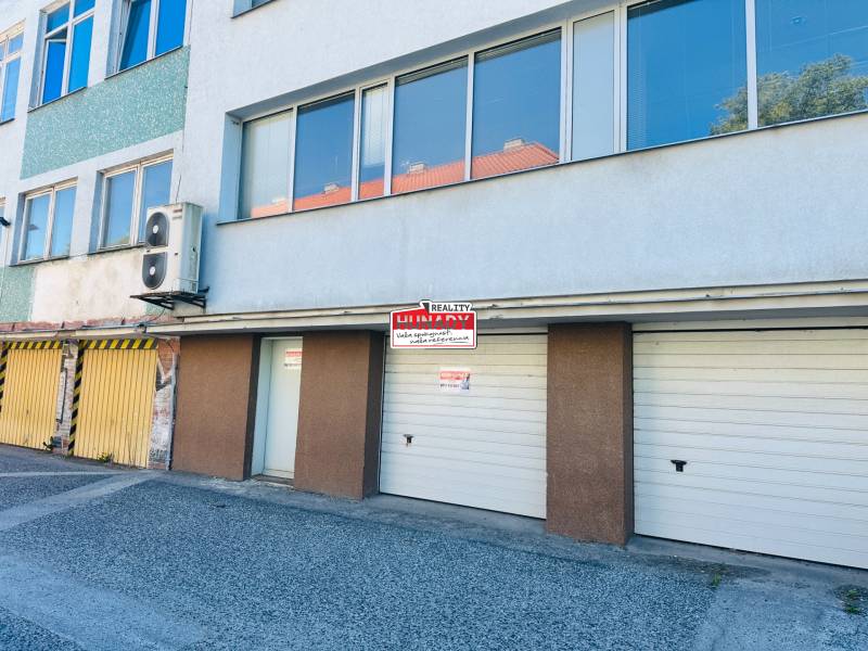 (16 m²) GARÁŽ NA PRENÁJOM V CENTRE - Garáže na Štefánikovom námestí v Spišskej Novej Vsi so vstupmi a reklamnou tabuľou.