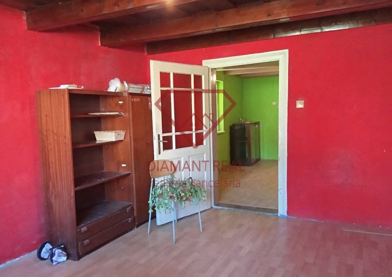 Na predaj stavebný pozemok 3655 m2 Zemianske Sady okr. Galanta  - Izba v rodinnom dome s červenými stenami, drevenou podlahou a nábytkom.
