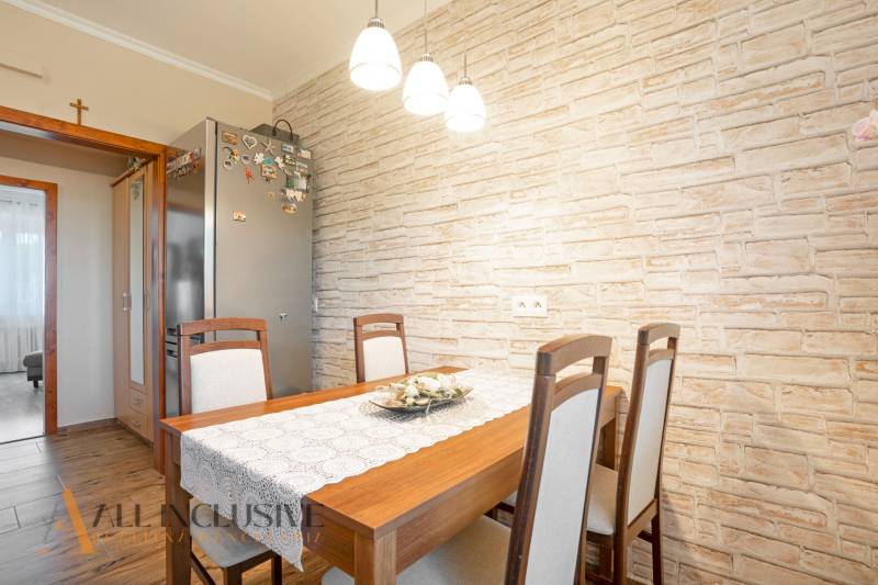 NA PREDAJ ZREKONŠ. 2-IZBOVÝ BYT S BALKÓNOM, GABČÍKOVO - Jedáleň v 2-izbovom byte s dreveným stolom a tehlovým obkladom steny.