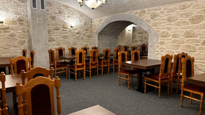 ODSTÚPENIE REŠTAURÁCIE v Nitre - Klenutý gastro priestor s kamennými stenami, dreveným stolom a elegantnými stoličkami.
