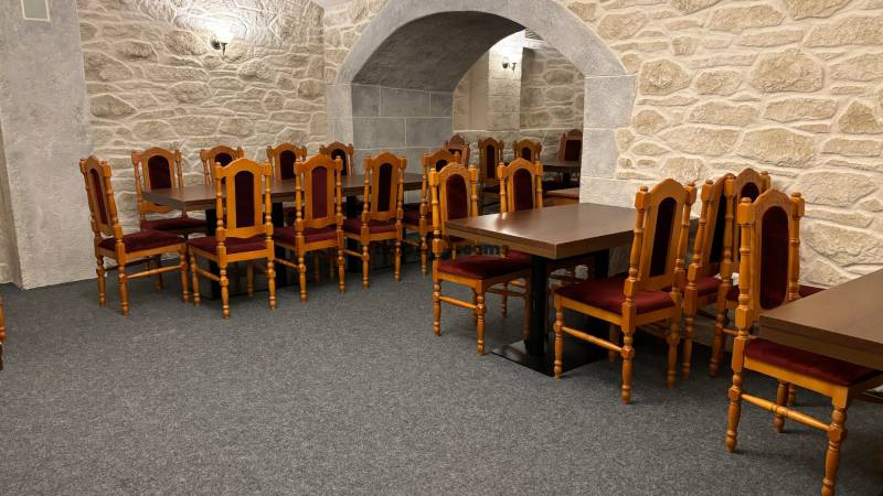 ODSTÚPENIE REŠTAURÁCIE v Nitre - Kamenná miestnosť s drevenými stoličkami, koberec a gastro priestory reštauračného štýlu.