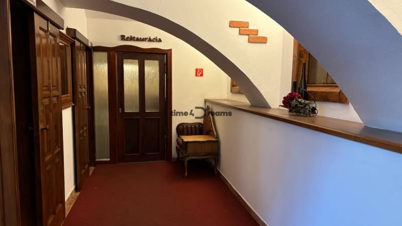 ODSTÚPENIE REŠTAURÁCIE v Nitre - Chodba s drevenými dverami vedie do reštaurácie, zdobená je stenou z tehál.