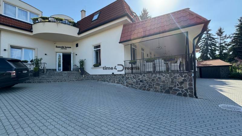 NA PREDAJ hotel s reštauráciou - Pohľad na budovu obklopenú zelenou, hotely ponúkajúce ubytovanie na nádvorí.