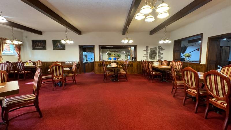 NA PREDAJ hotel s reštauráciou - Reštaurácia s dreveným stropom a červeným kobercom ponúka útulné prostredie pre hostí.
