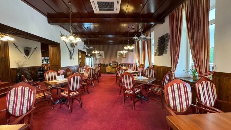 NA PREDAJ hotel s reštauráciou - Interiér reštaurácie so stoličkami a stolmi, drevené obloženie a dekoračné meče. Hotely a penzióny.