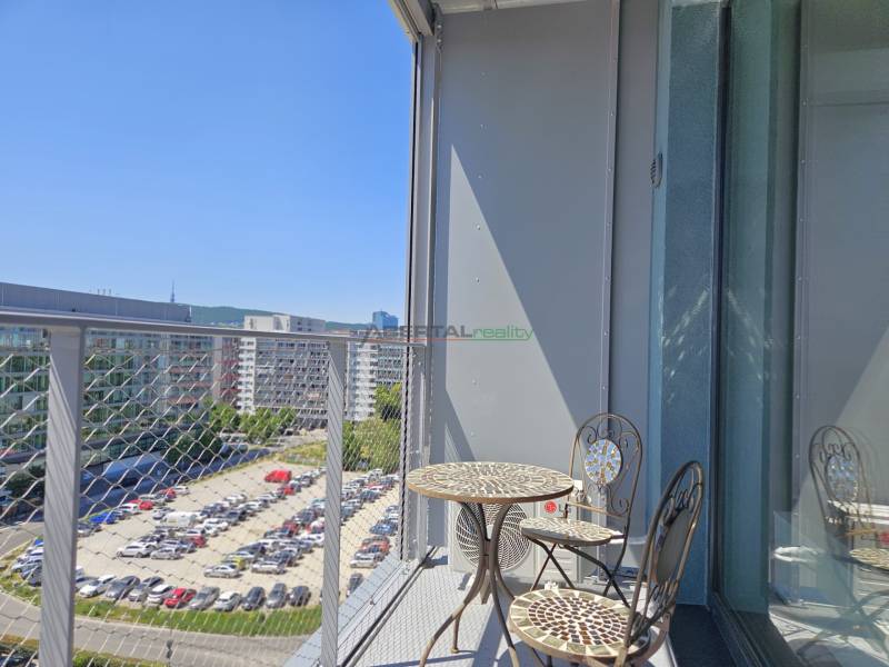 PRENÁJOM- 1i byt, klima, parking, loggia,Olivia Residence, Rožňavska - Balkón s kovovým stolom a stoličkami, výhľad na Rožňavskú ulicu v Bratislave.