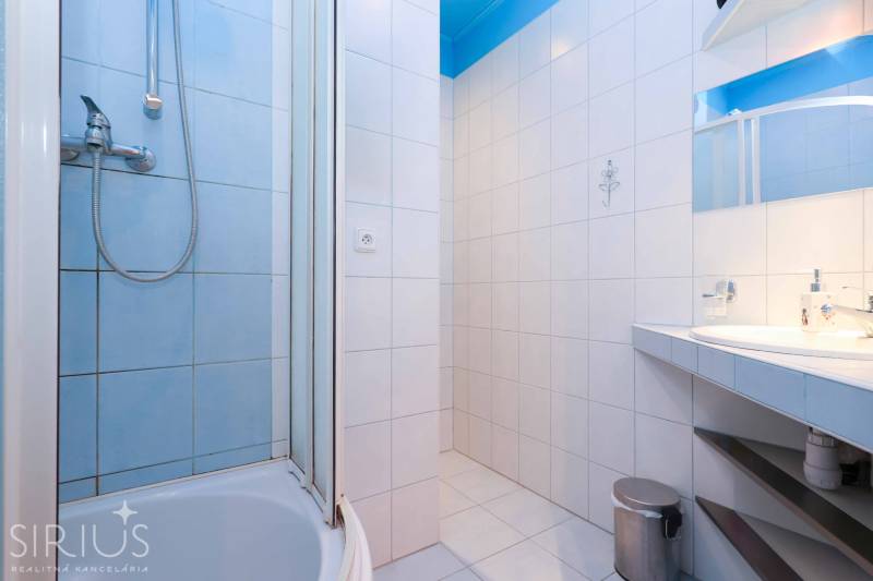 VYHĽADÁVANÁ 2-garsónka DE-LUXE v NAJVYHĽADÁVANEJŠEJ lokalite PETRŽALKY - Kúpeľňa v dvojgarsónke s bielymi obkladmi, sprchou a umývadlom.