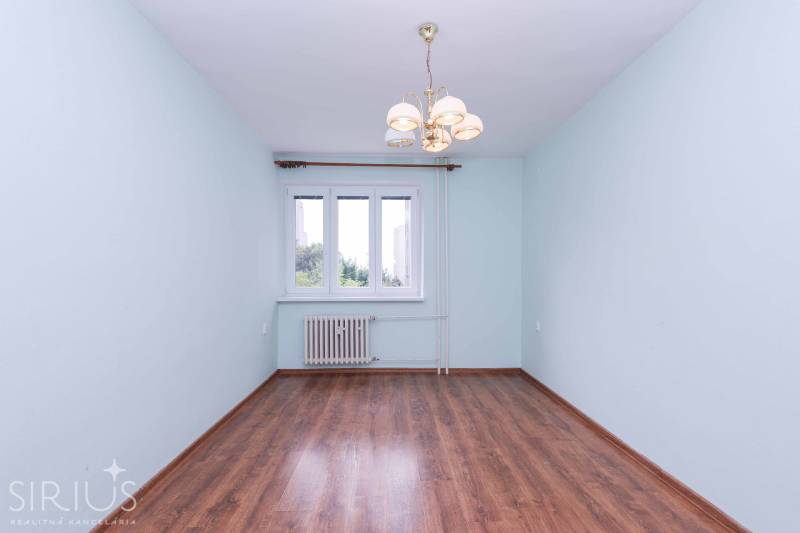 BÝVANIE NA HRADOM KOPCI - 3i byt, 90 m2 s balkónom, SVETLÁ ulica - Priestranná miestnosť v 3-izbovom byte s parketami a lustrom.