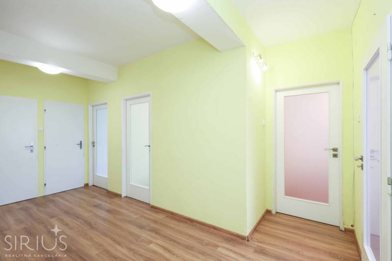 BÝVANIE NA HRADOM KOPCI - 3i byt, 90 m2 s balkónom, SVETLÁ ulica - Chodba so štyrmi bielymi dverami v 3-izbovom byte s drevenou podlahou.