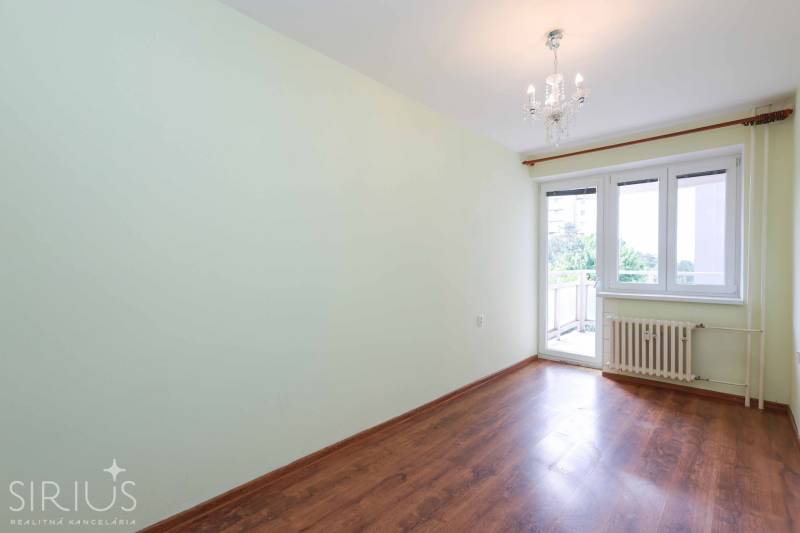 BÝVANIE NA HRADOM KOPCI - 3i byt, 90 m2 s balkónom, SVETLÁ ulica - Prázdna izba s laminátovou podlahou a balkónovými dvermi v 3-izbovom byte.