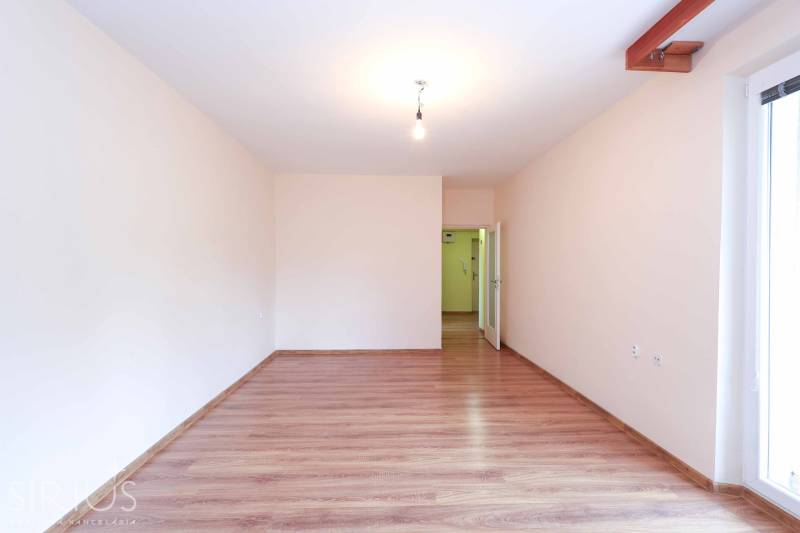 BÝVANIE NA HRADOM KOPCI - 3i byt, 90 m2 s balkónom, SVETLÁ ulica - Priestranná miestnosť s drevenou podlahou a bielymi stenami v 3-izbovom byte.